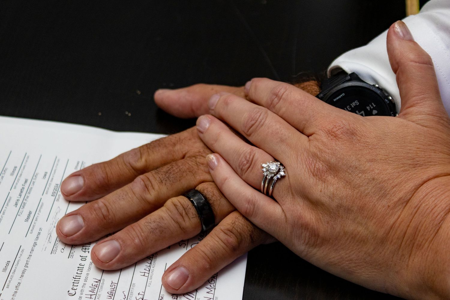 Close up of hands showing wedding rings on marriage certificate.