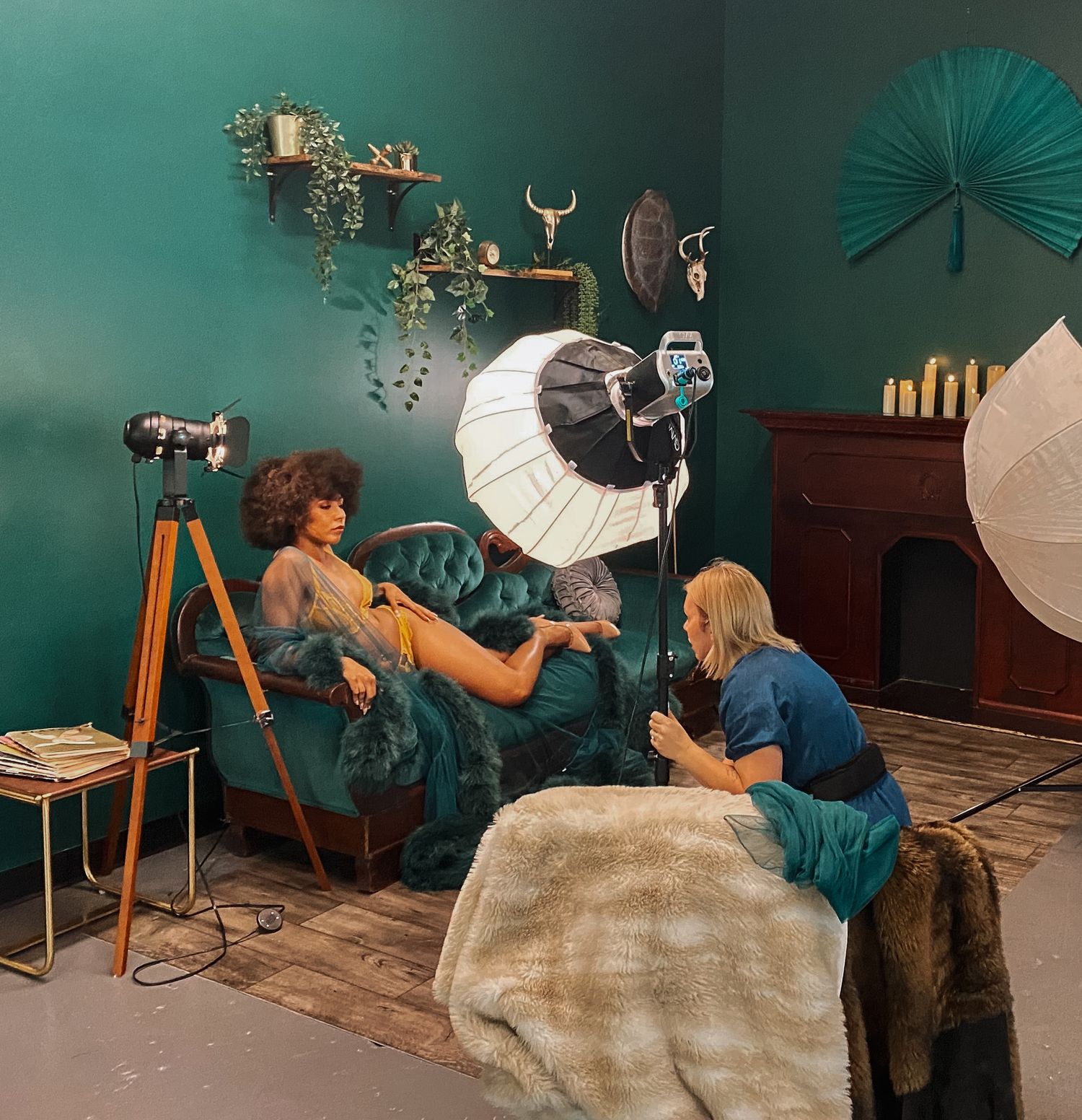Behind-the-scenes photo shoot setup in teal room with professional lighting equipment.