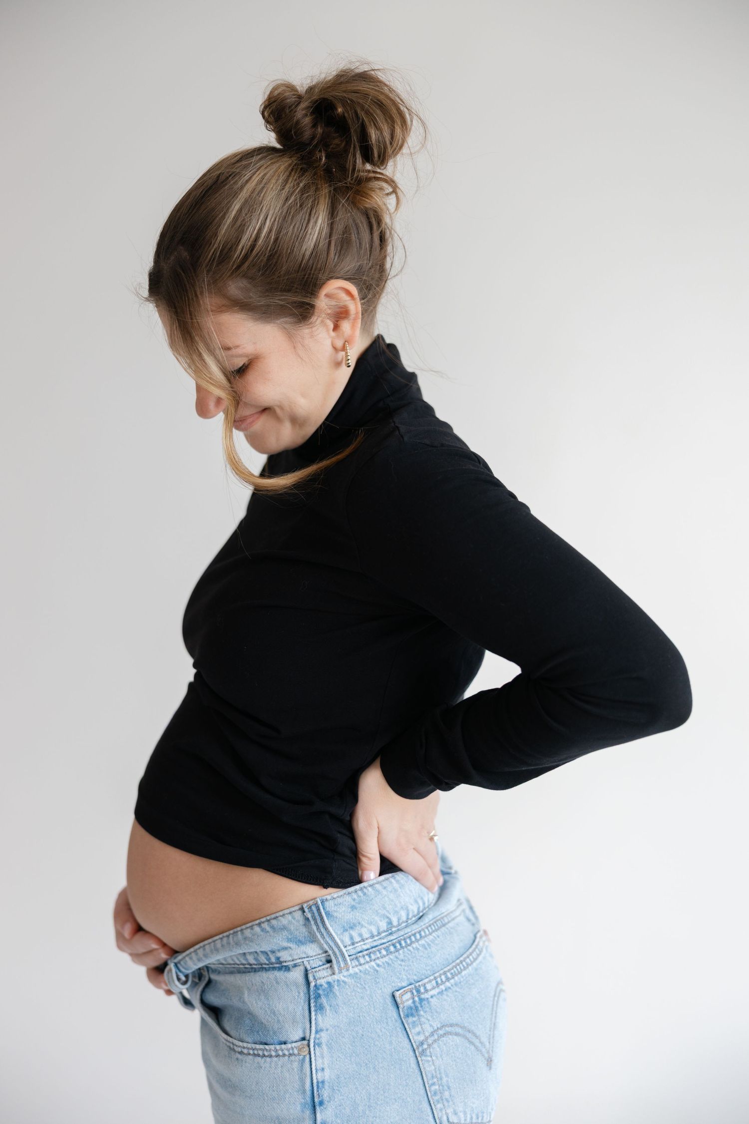 Person in black turtleneck and blue jeans shown from behind against white background in three different poses.