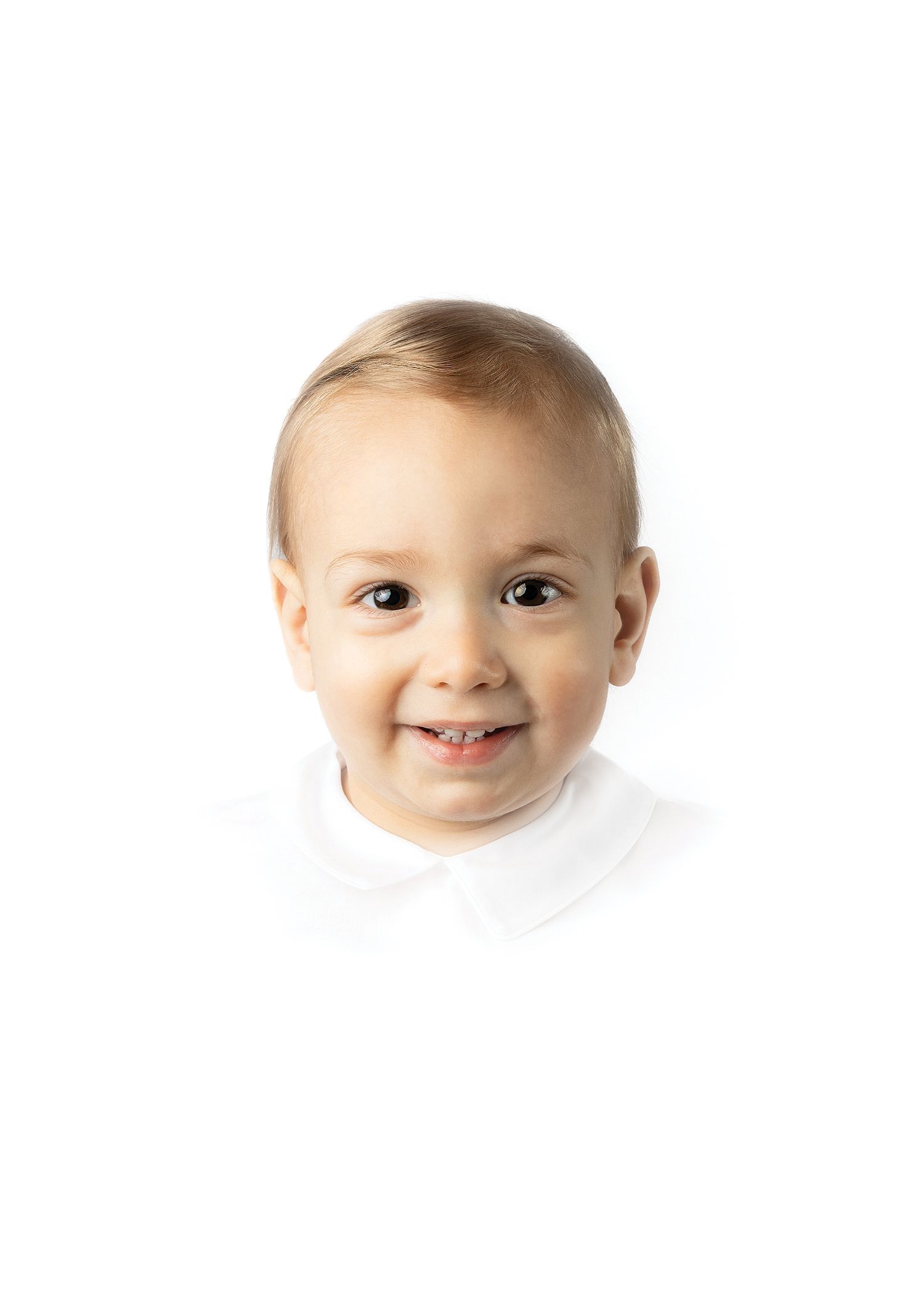 Smiling toddler boy with blonde hair wearing a white collared shirt against a white background.