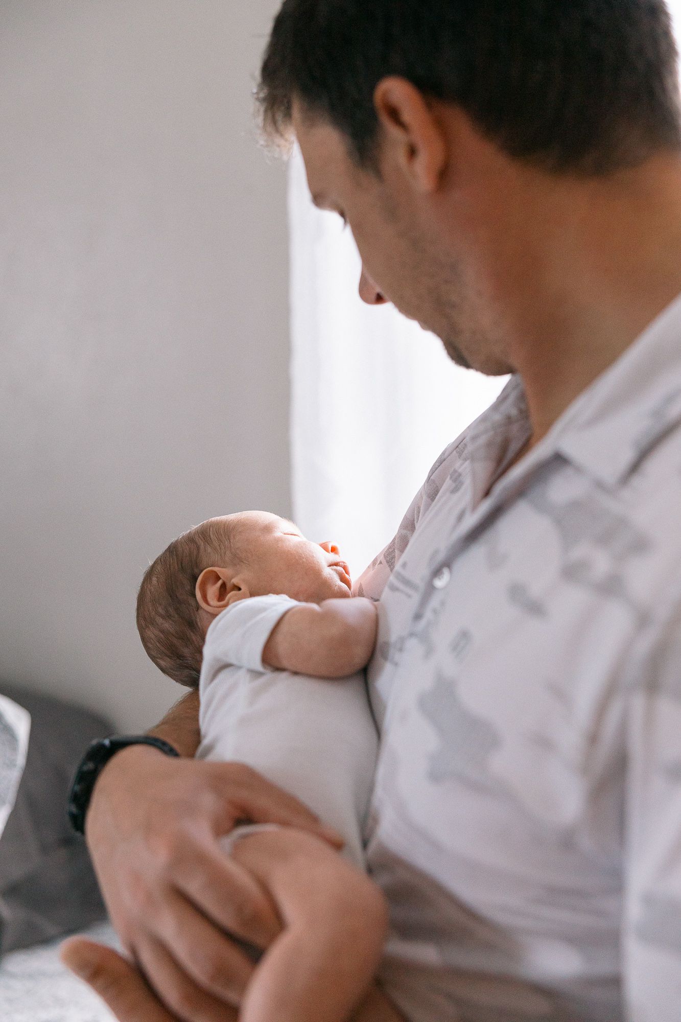 photo of new dad holding newborn baby in arms