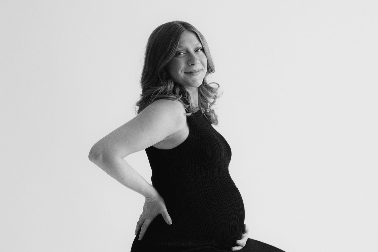 Four black and white studio portraits showing a figure in a black outfit posing against a light background.