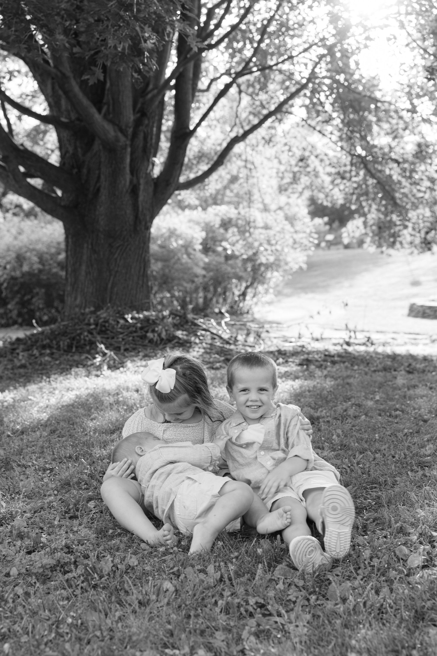 Series of black and white photos showing a child lying on grass under dappled sunlight.