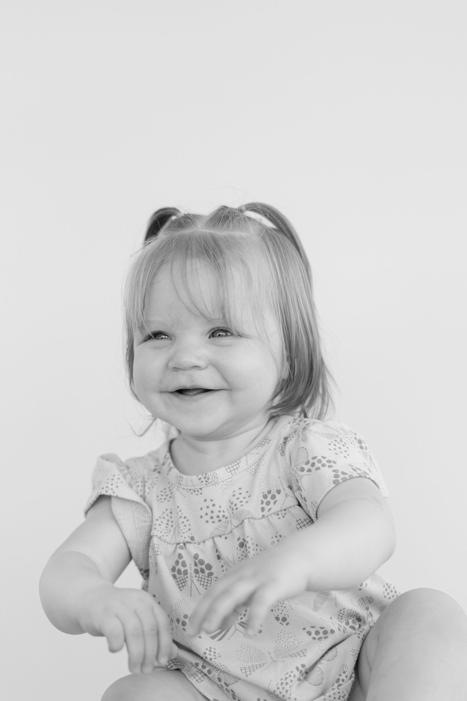 A series of four black and white photos showing a small child in a lace collar dress making playful expressions.