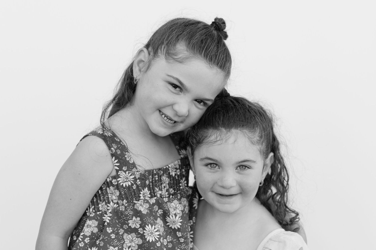 Two children in black and white photo smiling together while wearing casual clothing.