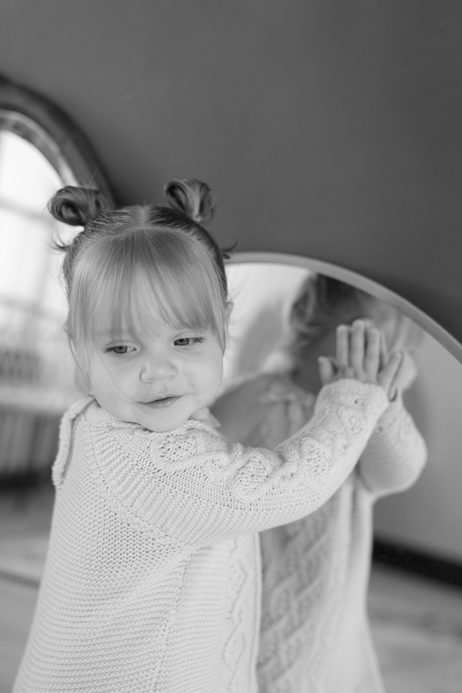 A series of black and white photos showing a child in a white knit sweater making playful gestures.