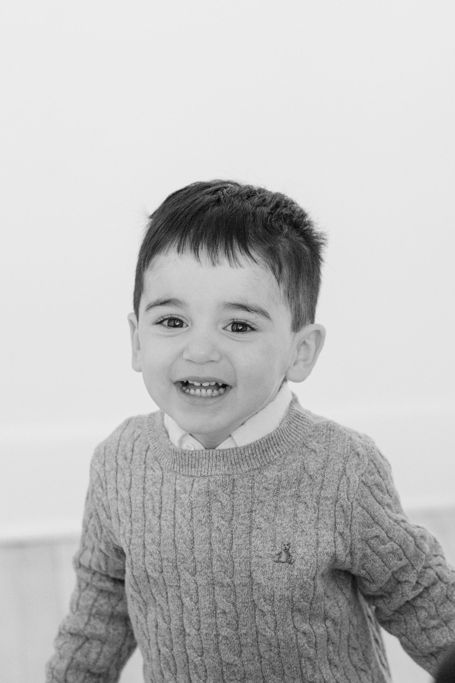 Black and white photo sequence showing a young child in a cable knit sweater making playful expressions.