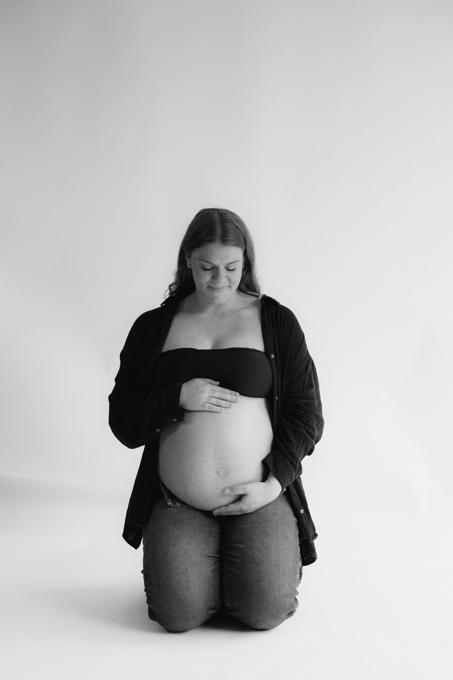 A black and white photo series showing a pregnant figure in different seated poses against a white background.