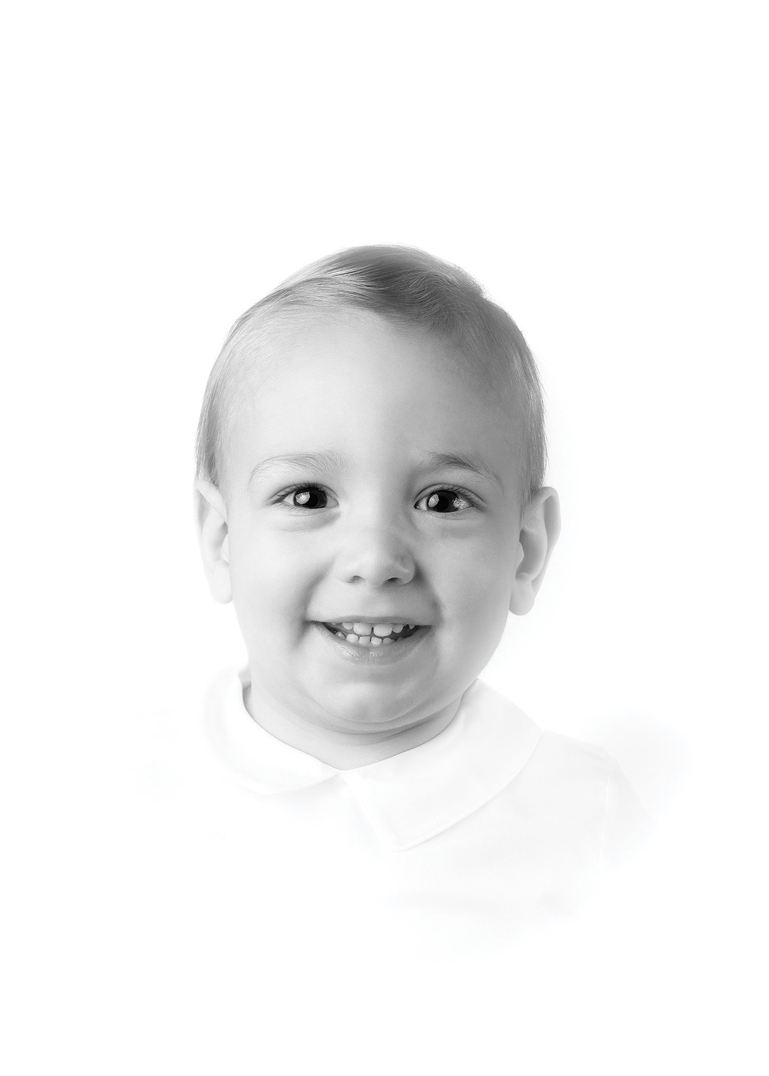 Black and white portrait of a smiling toddler boy with short hair wearing a white collared shirt.