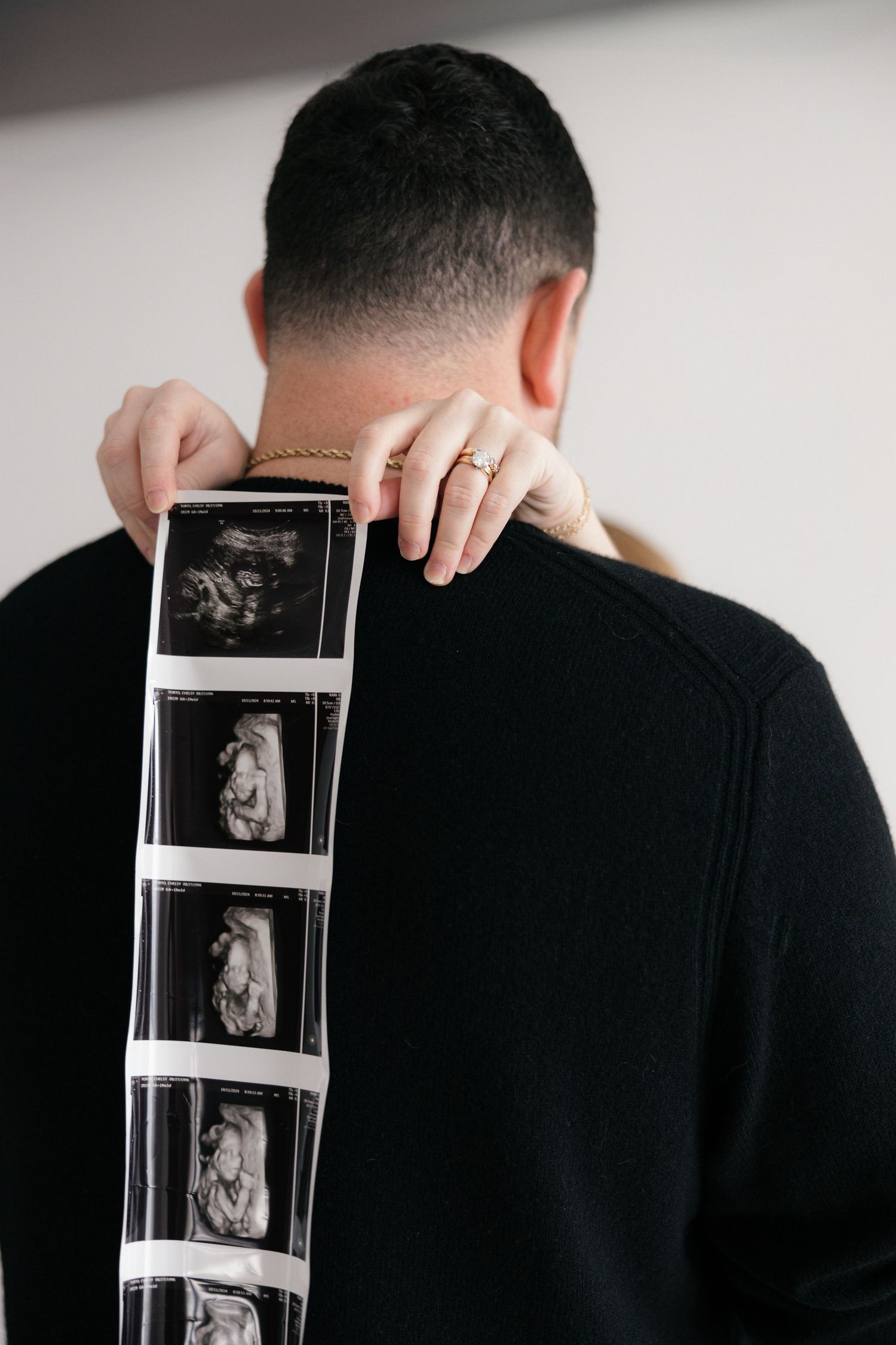 A person in black holds up film negatives against a light background showing a progression of intimate moments.