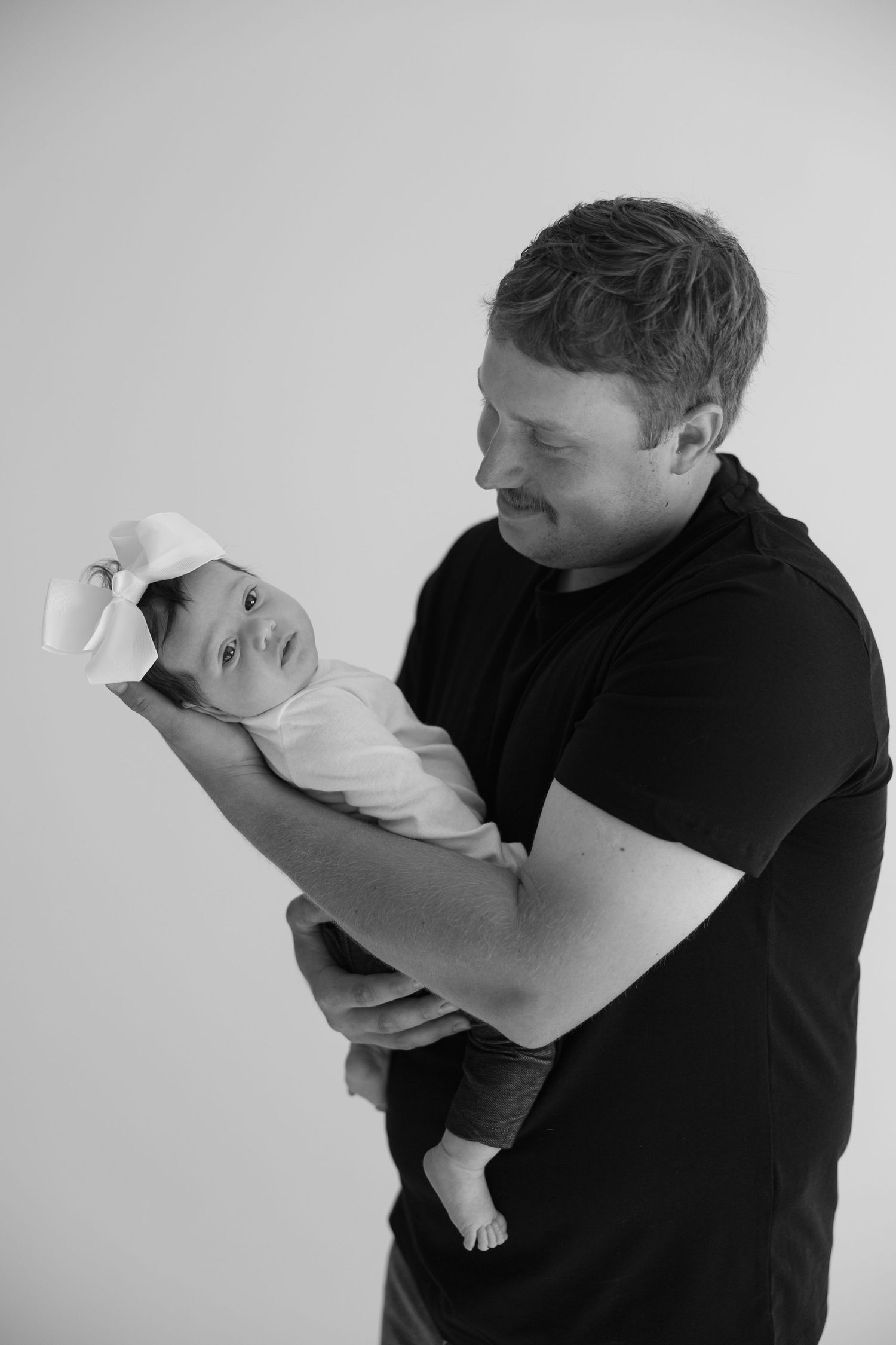 A person in black shirt tenderly holds and gazes at a small white puppy in a progressive sequence of sweet moments.