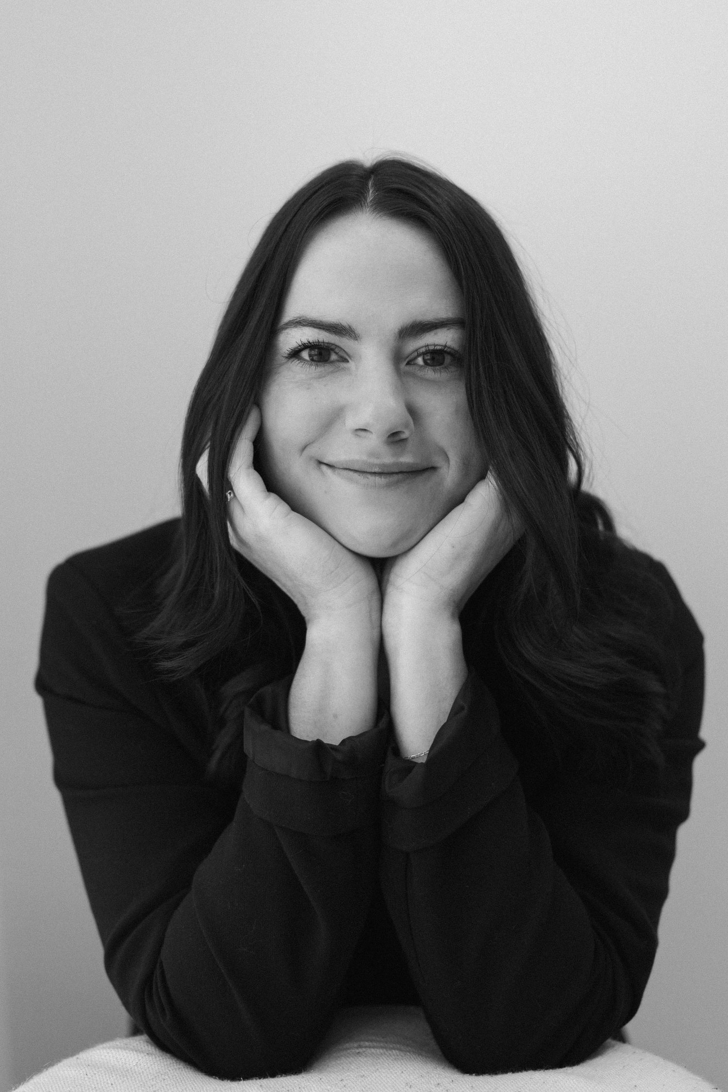 A black and white photo series showing different poses with dark hair and black clothing against a light background.