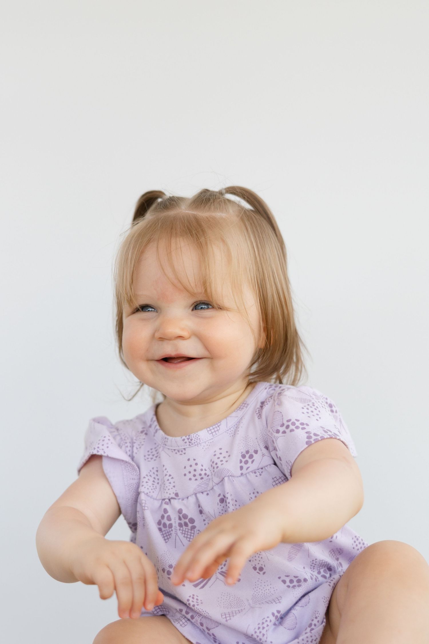 A child in a lavender eyelet dress laughs and plays in a series of candid photos against a white background.
