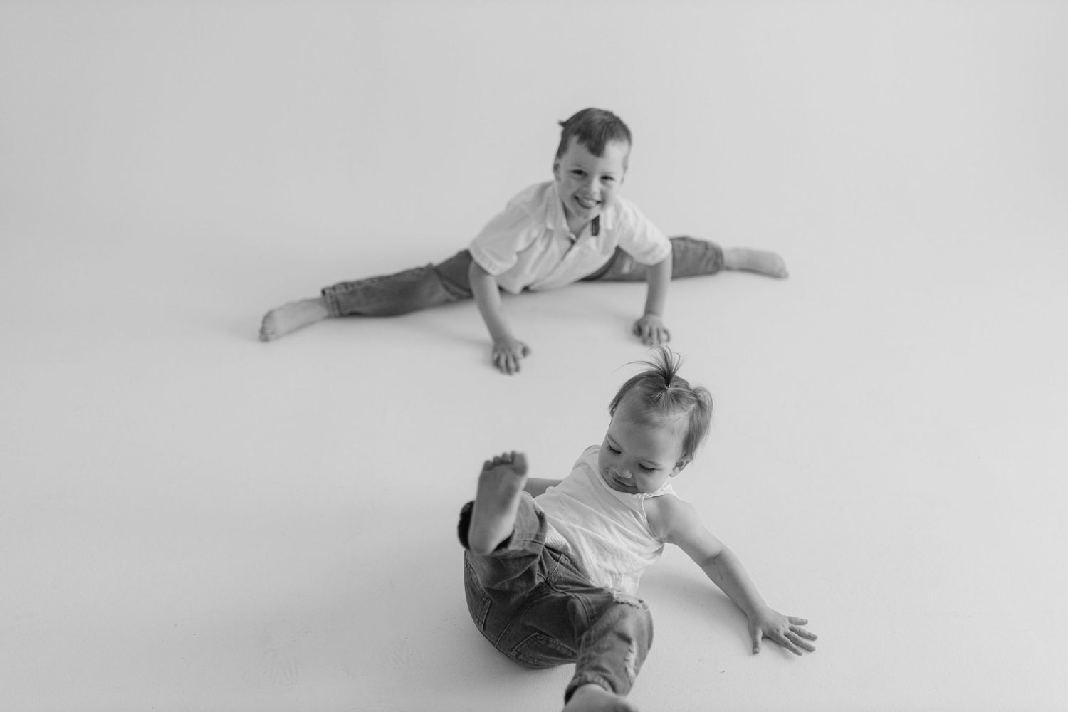 Two dancers perform black and white contemporary duet on the floor with graceful extended arm positions.