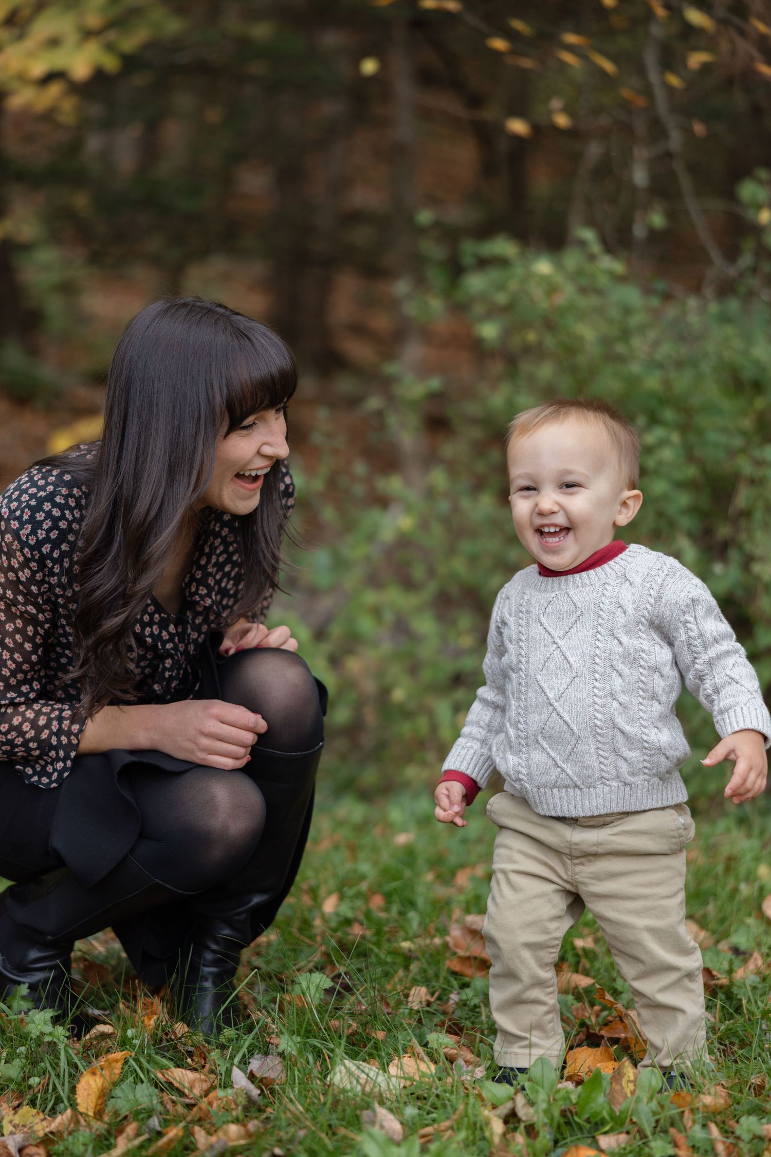 A joyful outdoor autumn scene with a small child in a white sweater playing in fallen leaves.