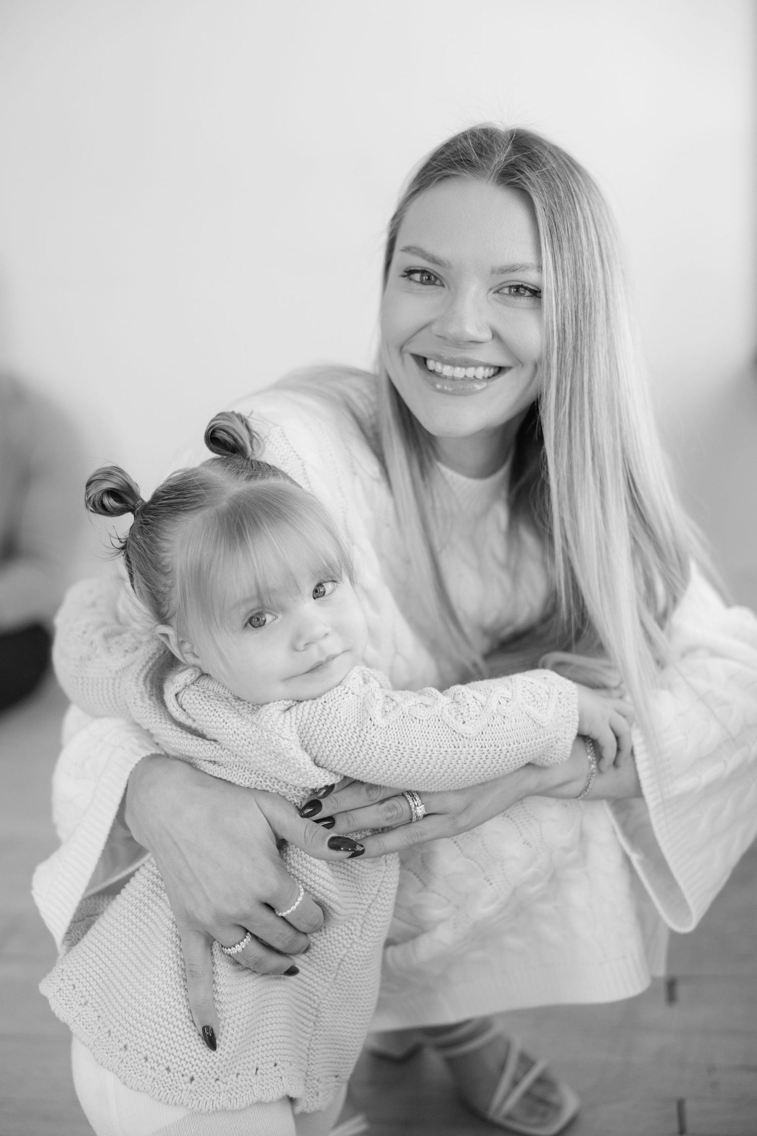 A black and white photo series shows tender moments between a parent and baby in matching white outfits.