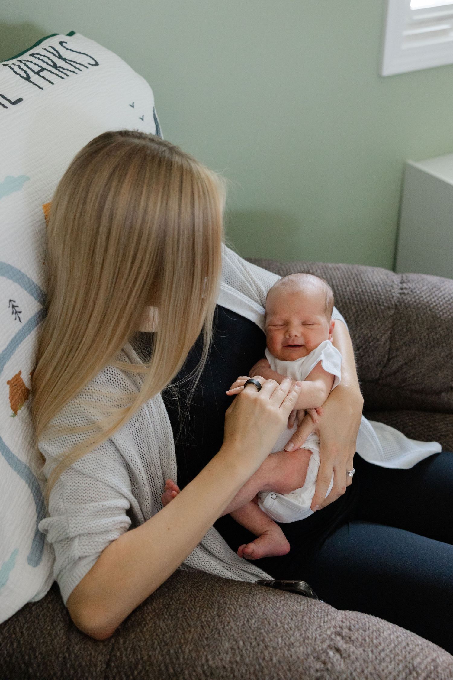 A series of four photos showing someone holding and feeding a newborn baby on a gray couch.
