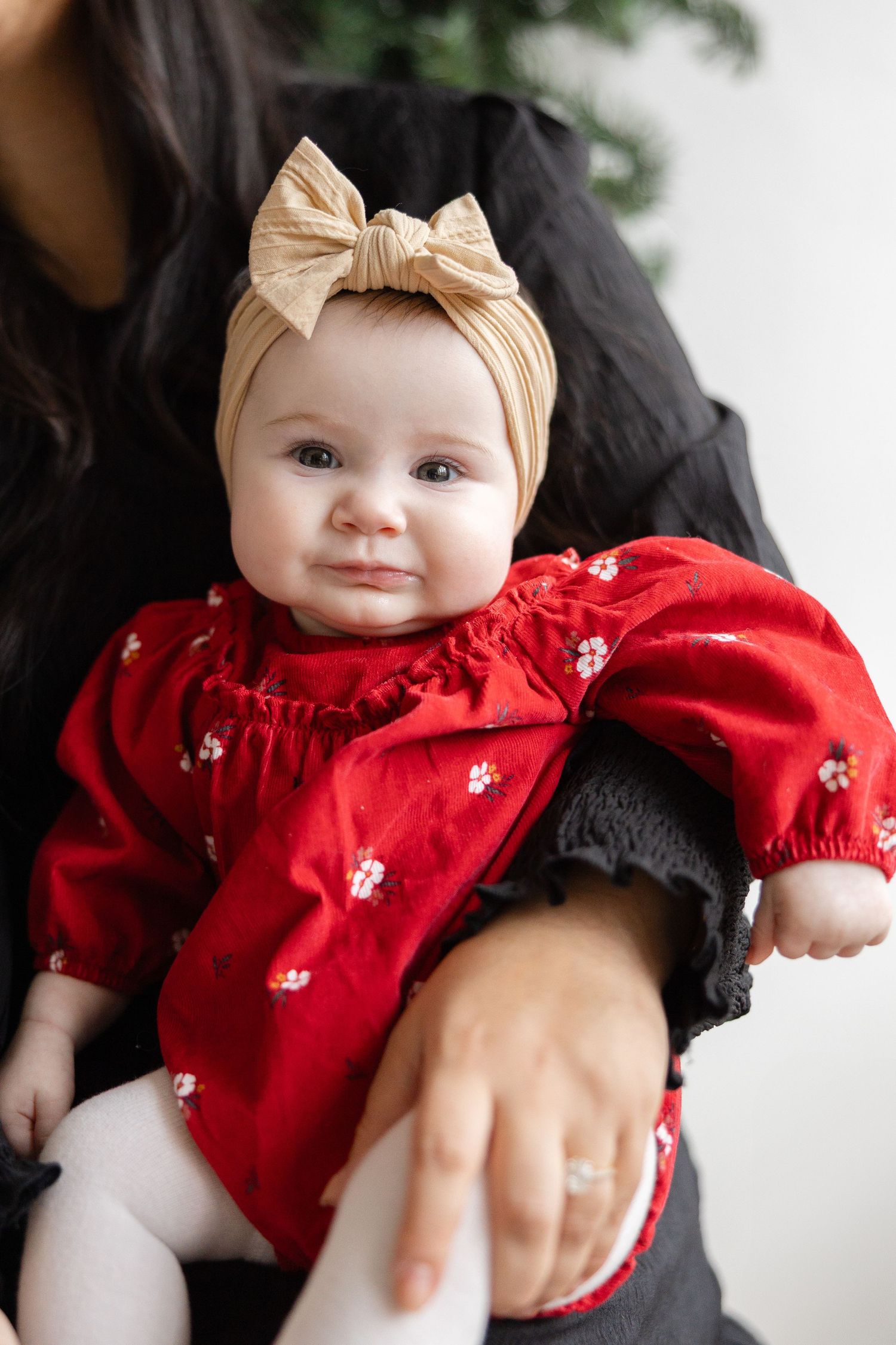 A baby wearing a red dress and beige bow headband is shown in a series of cropped photos.