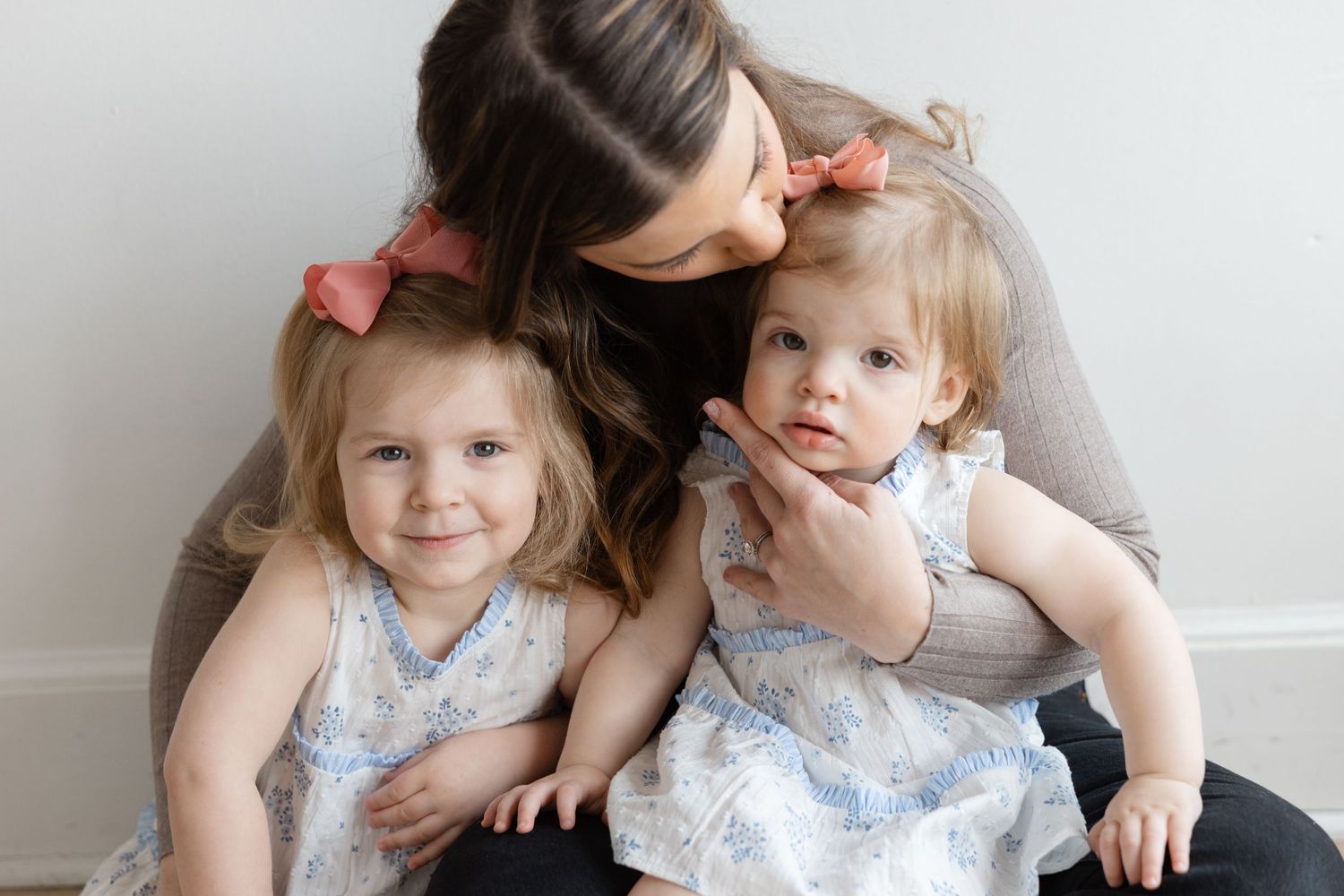 A sweet candid moment between parent and child sitting together against a white wall.