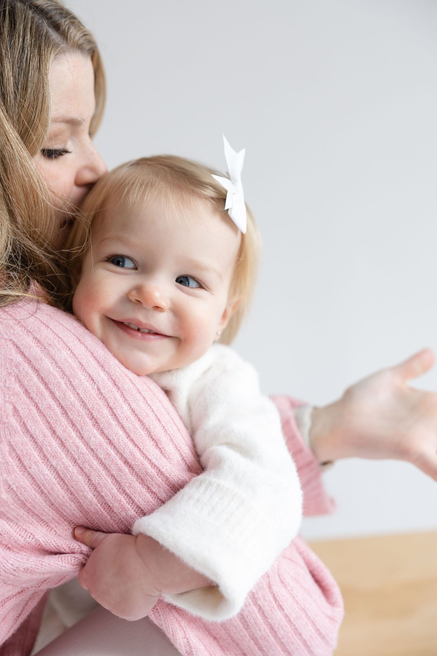 A series of tender moments showing a baby in a white sweater cuddling against a pink knit sweater.