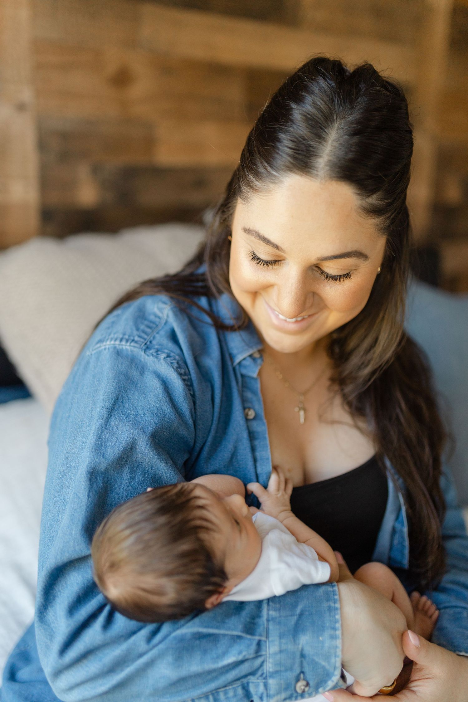 A tender moment of breastfeeding as a mother in a denim shirt nurtures her infant in a peaceful indoor setting.