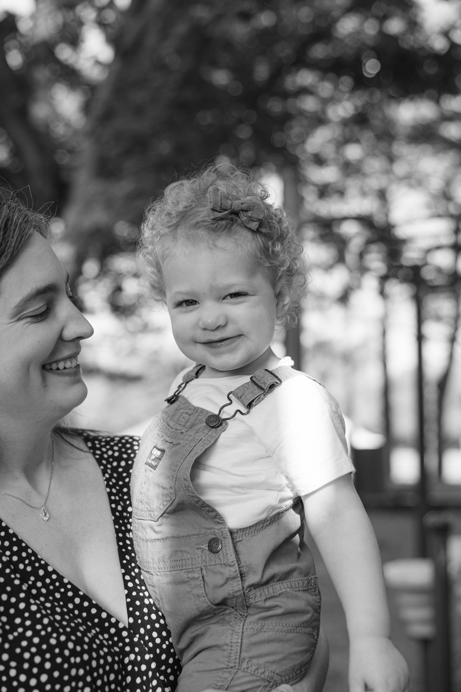 Black and white photo sequence showing joyful interaction between an adult in polka dots and child in overalls outdoors.