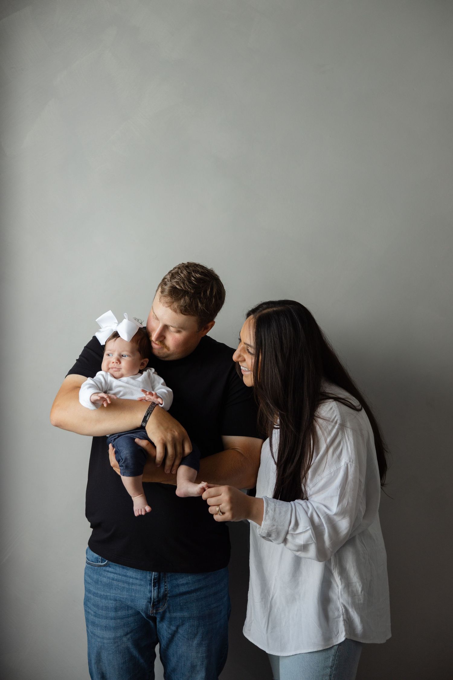 Four connected images show a family in casual attire posing playfully against a gray backdrop.