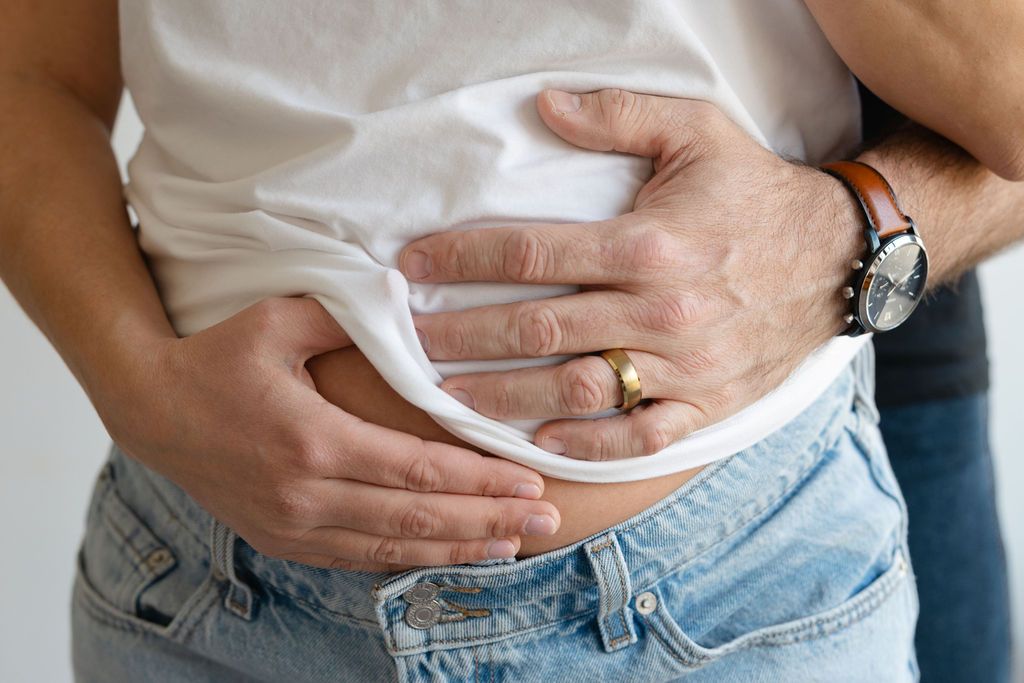 Row of people wearing jeans and holding their stomachs in discomfort, showing signs of digestive issues.