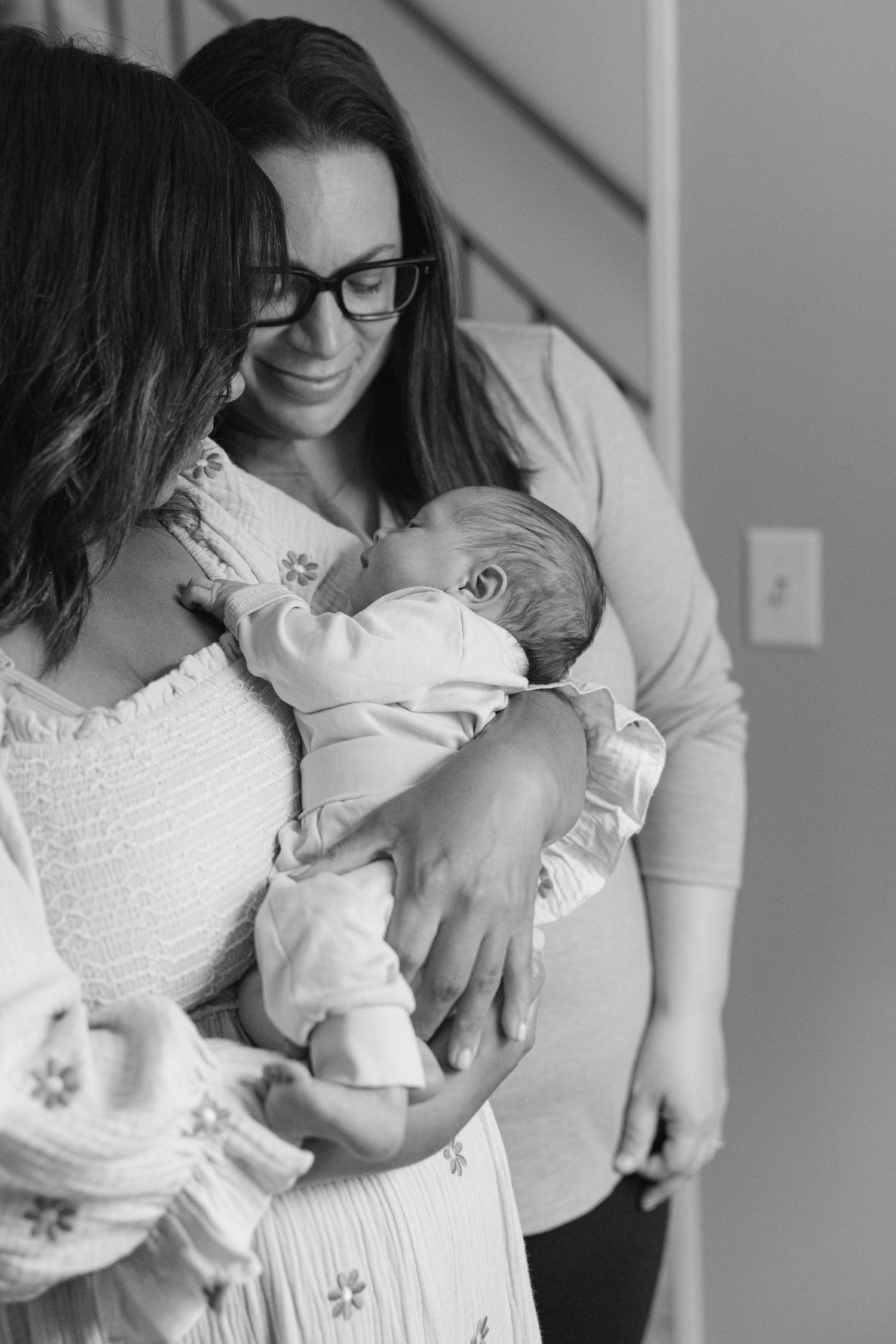 Black and white photo series showing tender moments between parent and baby in intimate indoor setting.