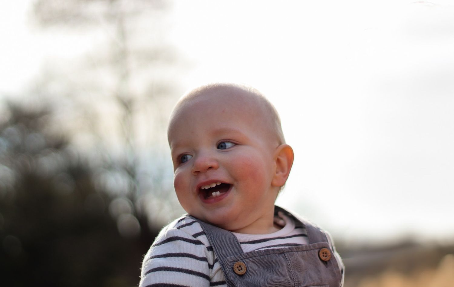 Baby boy laughing and looking to the left. Natural documentary photography