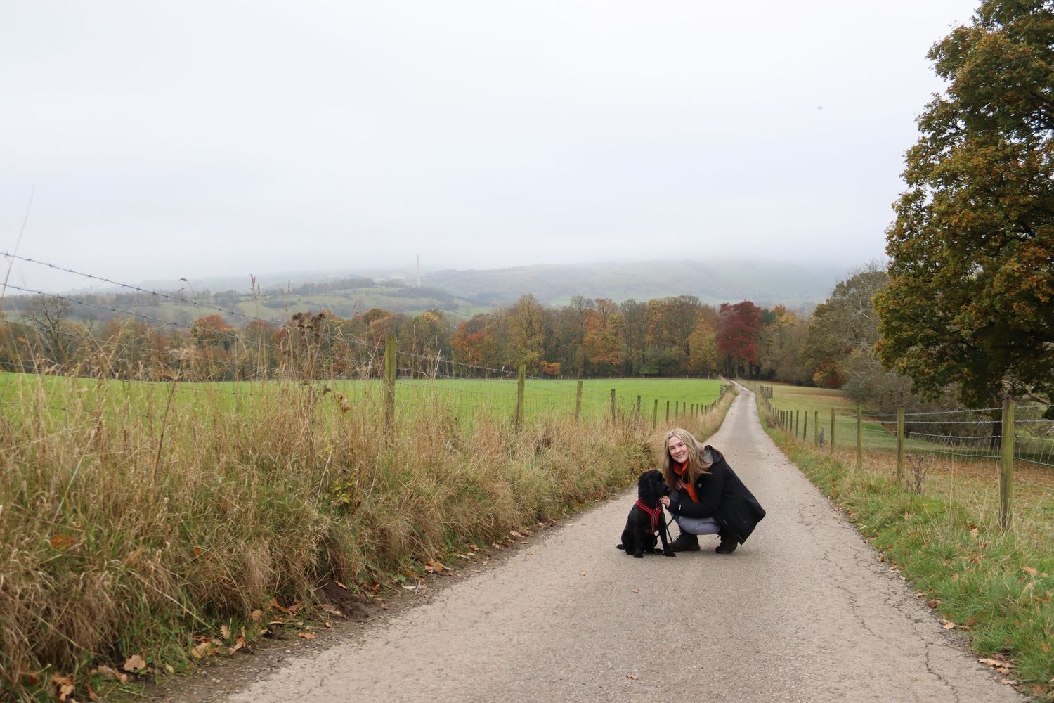 Photographer and her dog on a long windy pathway with autumnal trees