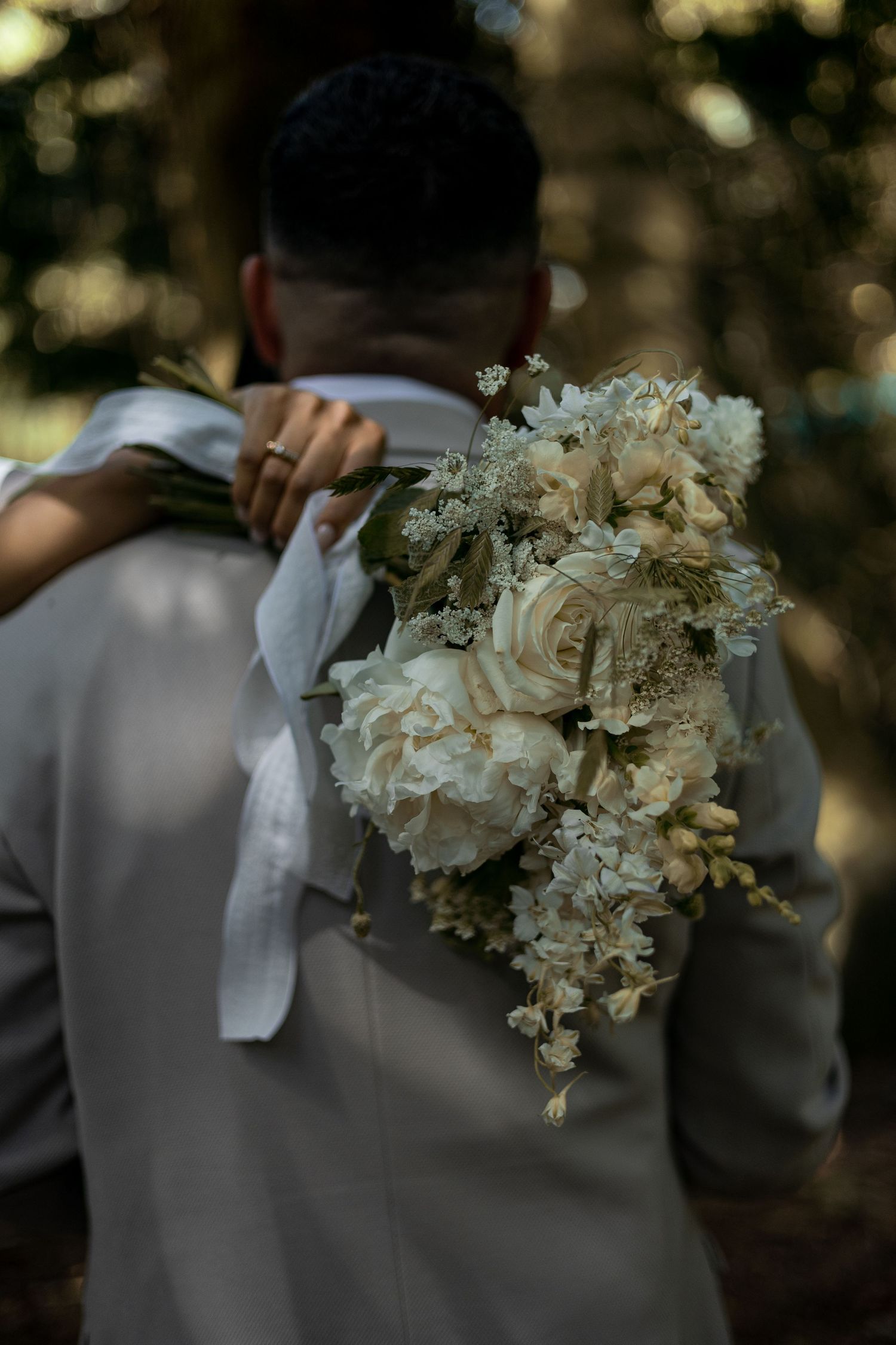 Bride draping her neutral bouquet over grooms shoulders