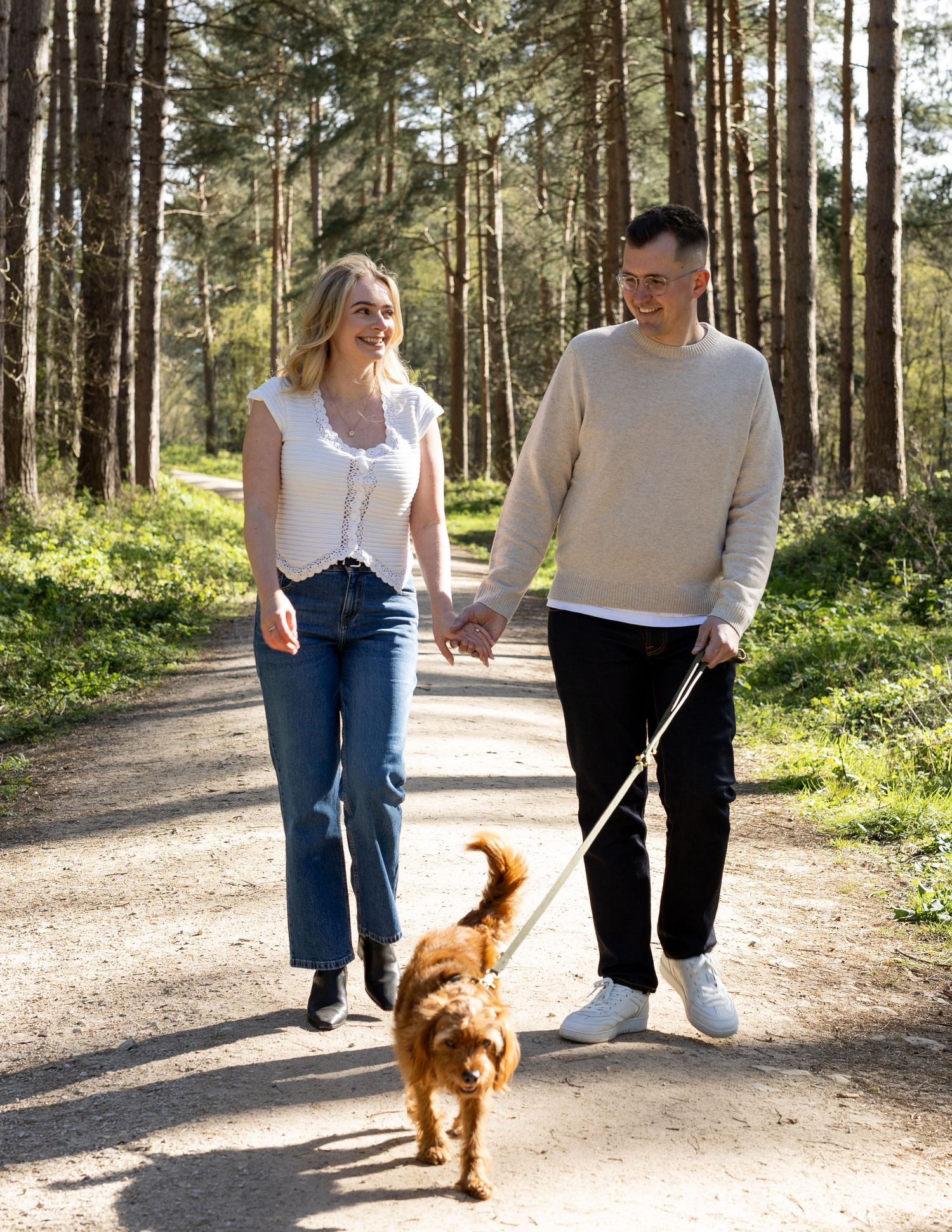 A couple walking hand in hand in the woods with their dog. Natural documentary photography, Nottingham.
