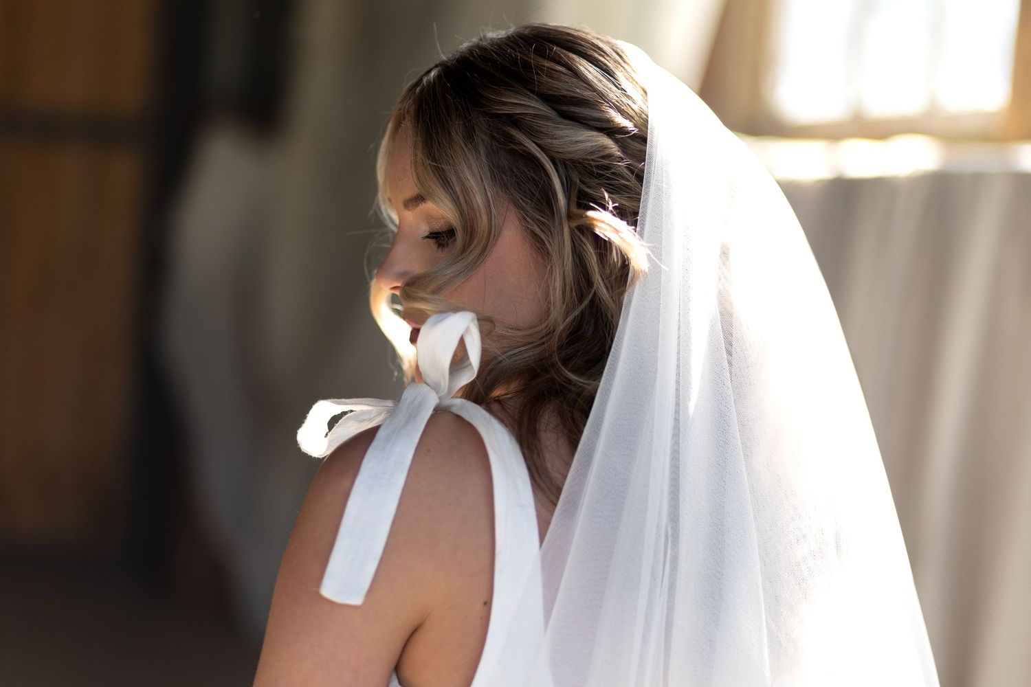 Bride looking over her shoulder. Golden hour. Bow detailed dress.