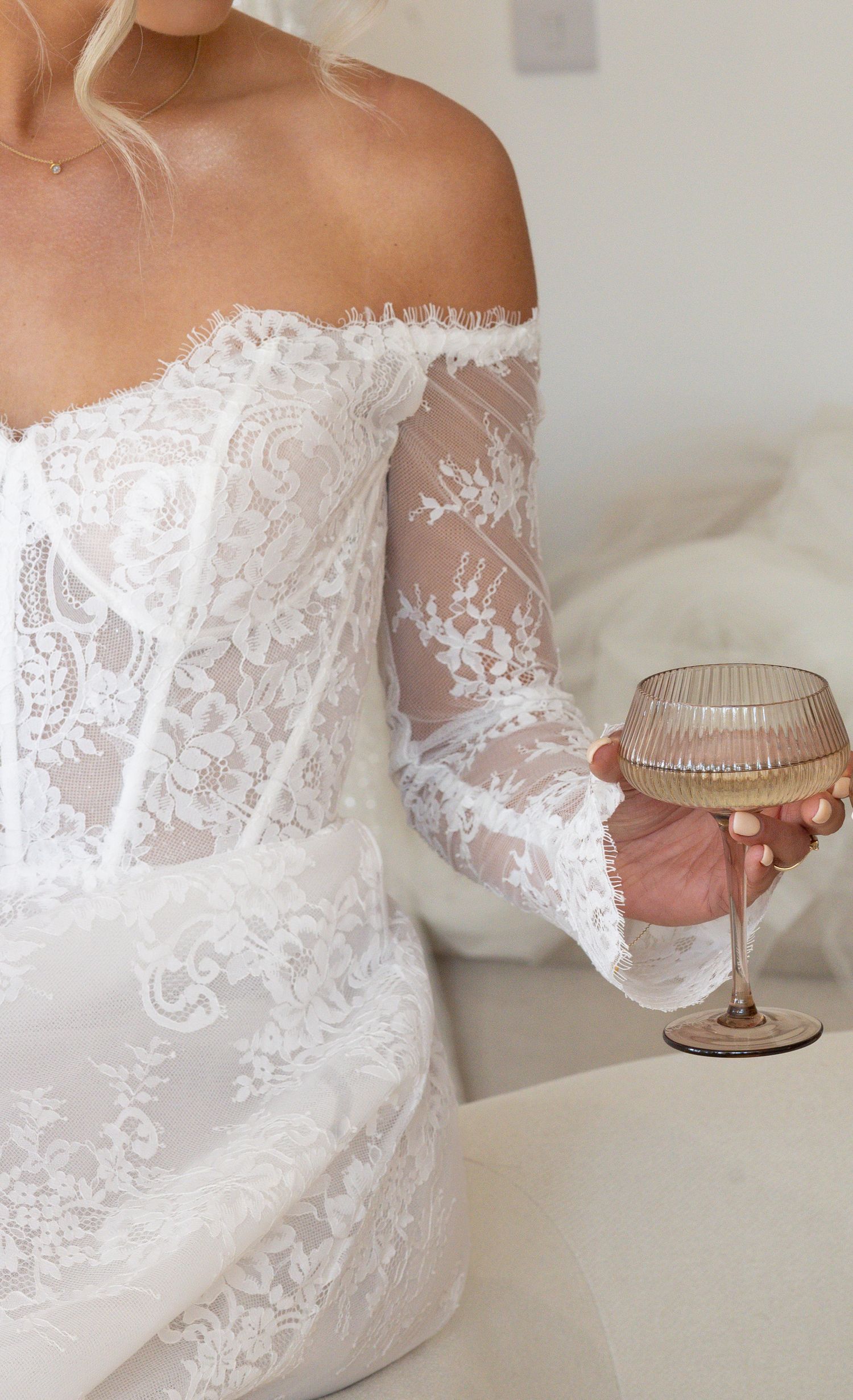 Shot of bride with a lace detailed dress holding a champagne coupe