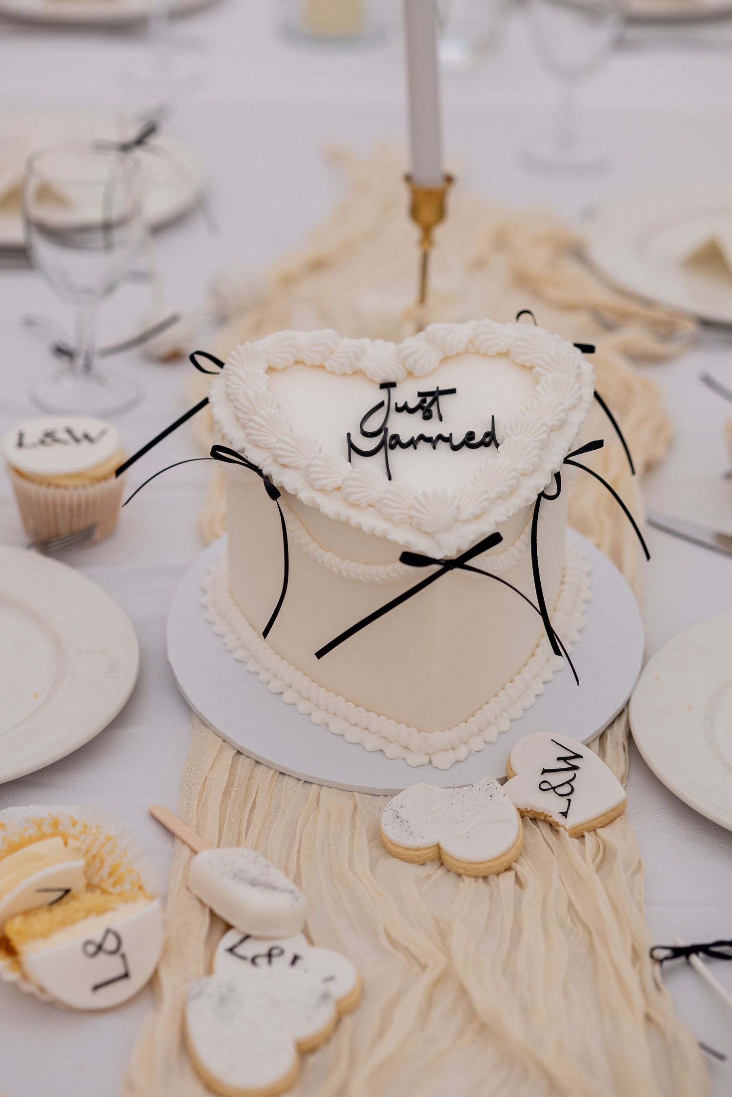 A beautiful heart shaped lambeth cake surrounded by cupcakes and sweet treats on a gorgeous styled wedding breakfast table.