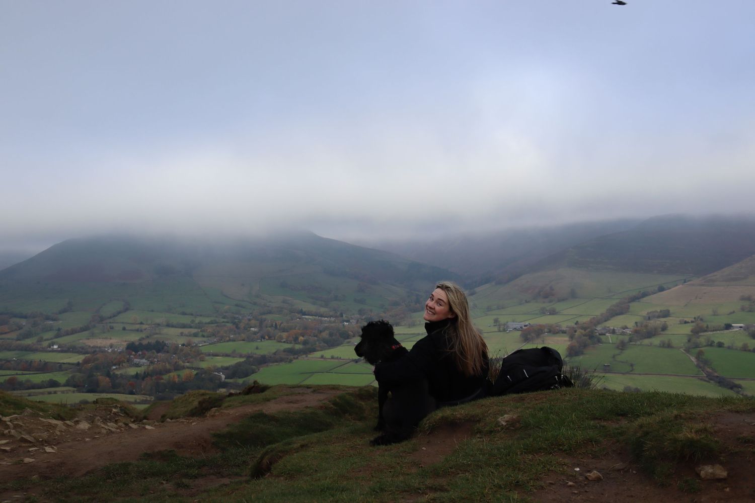 Photographer and her dog sat looking over at a beautiful landscape behind