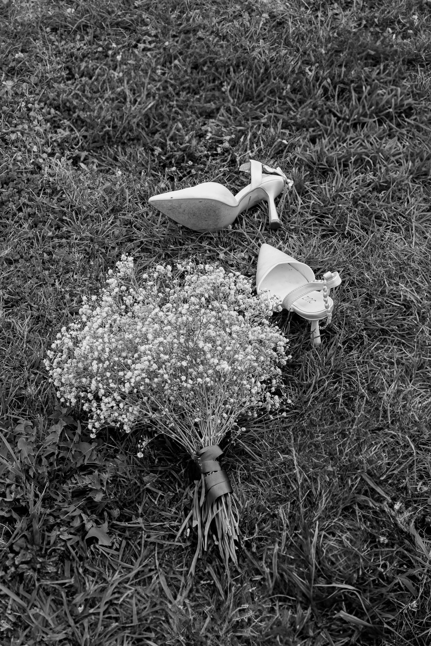 The brides shoes and bouquet laid on the grass after dancing all night
