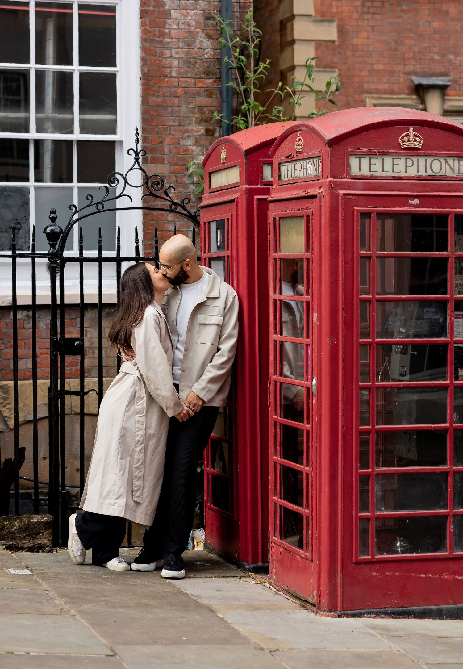Couple having a romantic kiss leaning on the red telephone boxes. Natural documentary wedding photography