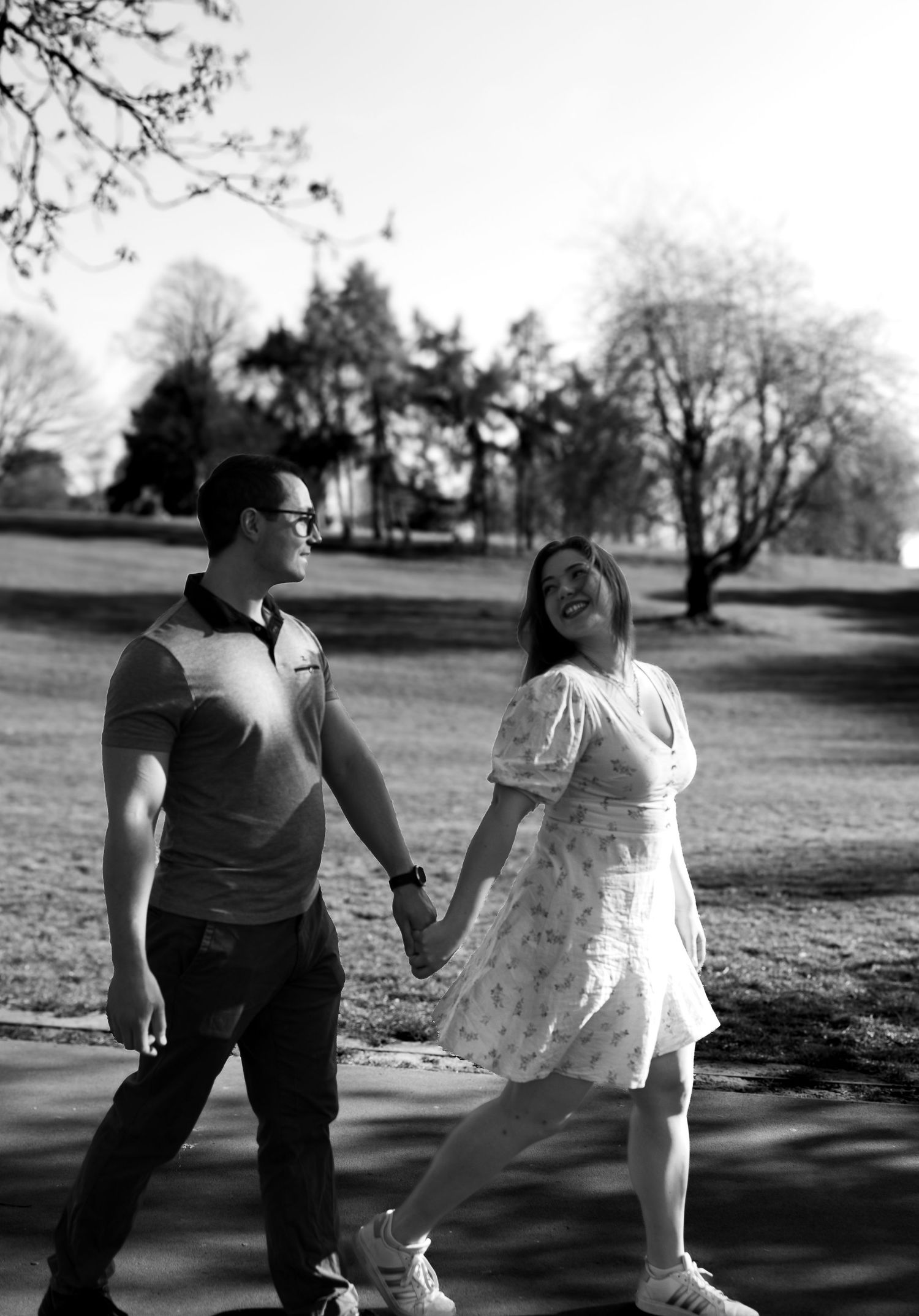 Couple strolling hand in hand through the park looking at each other in love. Natural documentary wedding photography