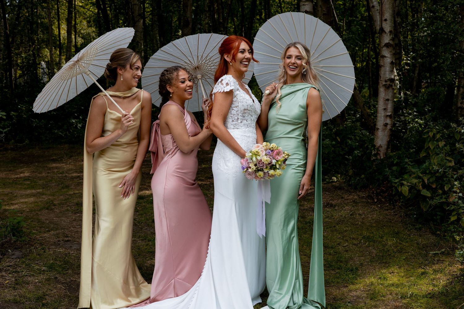A bride and her bridesmaids in pastel laughing at Sherwood Glade in the Midlands.
