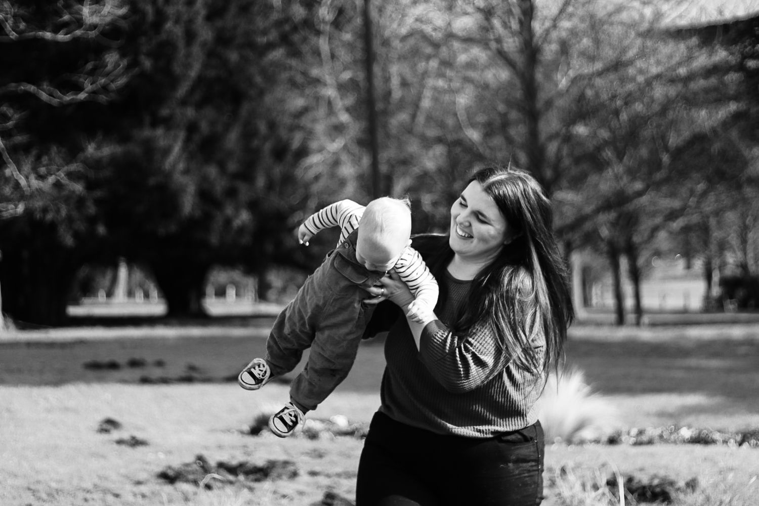 Mother and son in black and white. Mum spinning son in the air laughing. Natural documentary photography