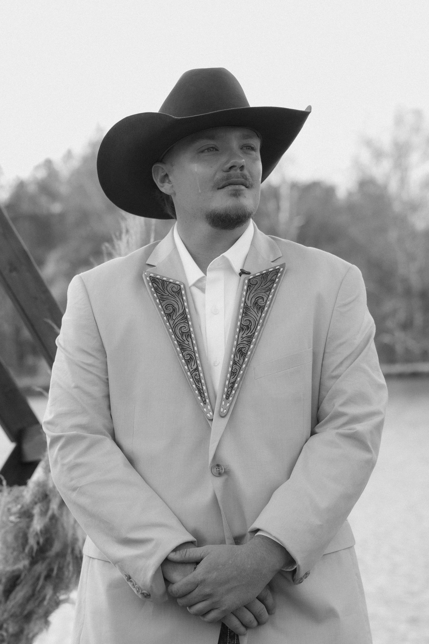 Groom standing at lakefront ceremony wearing custom leather lapels during Taylor Estate wedding in Rome GA