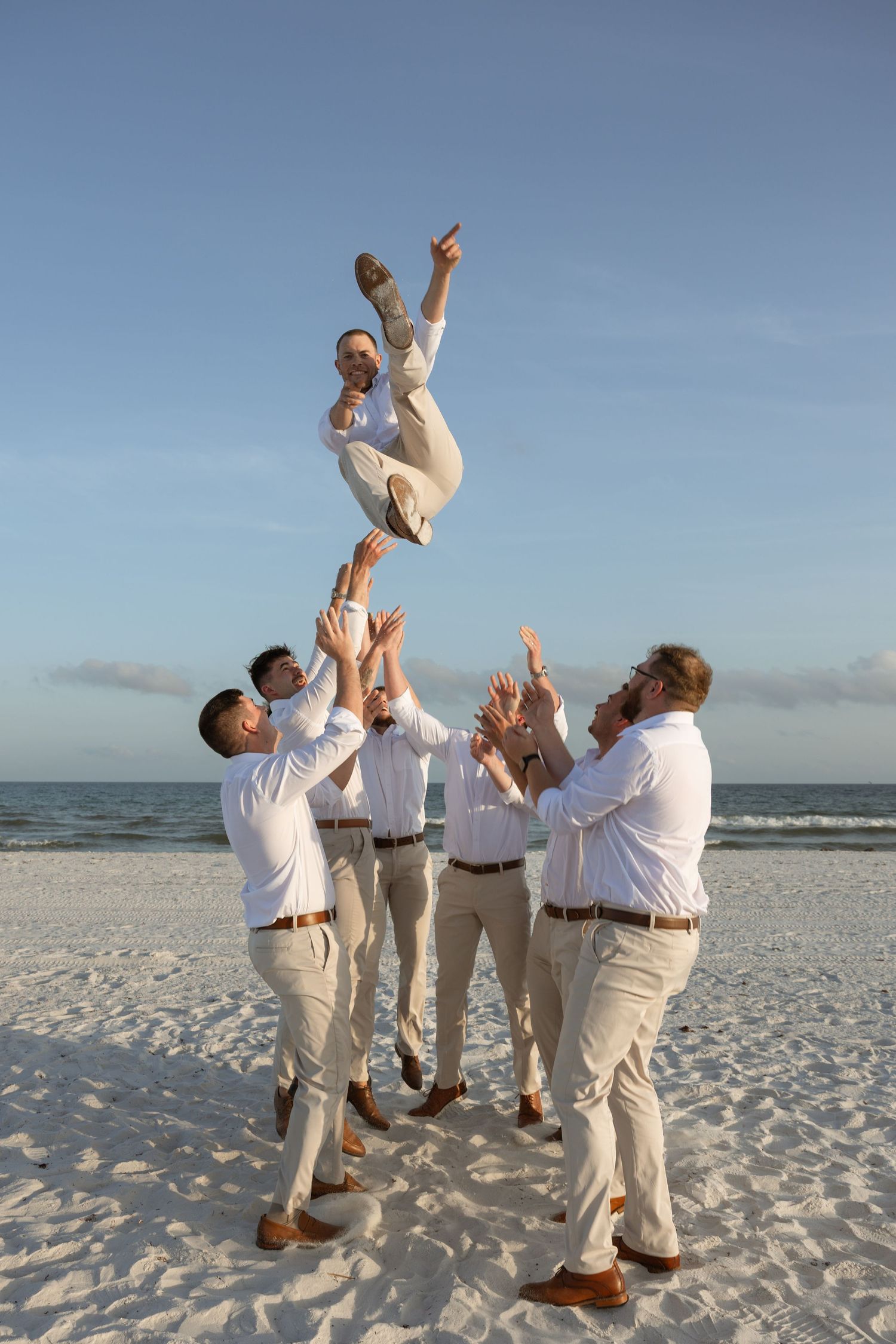 Playful groomsmen on the sand during Navarre Beach micro wedding