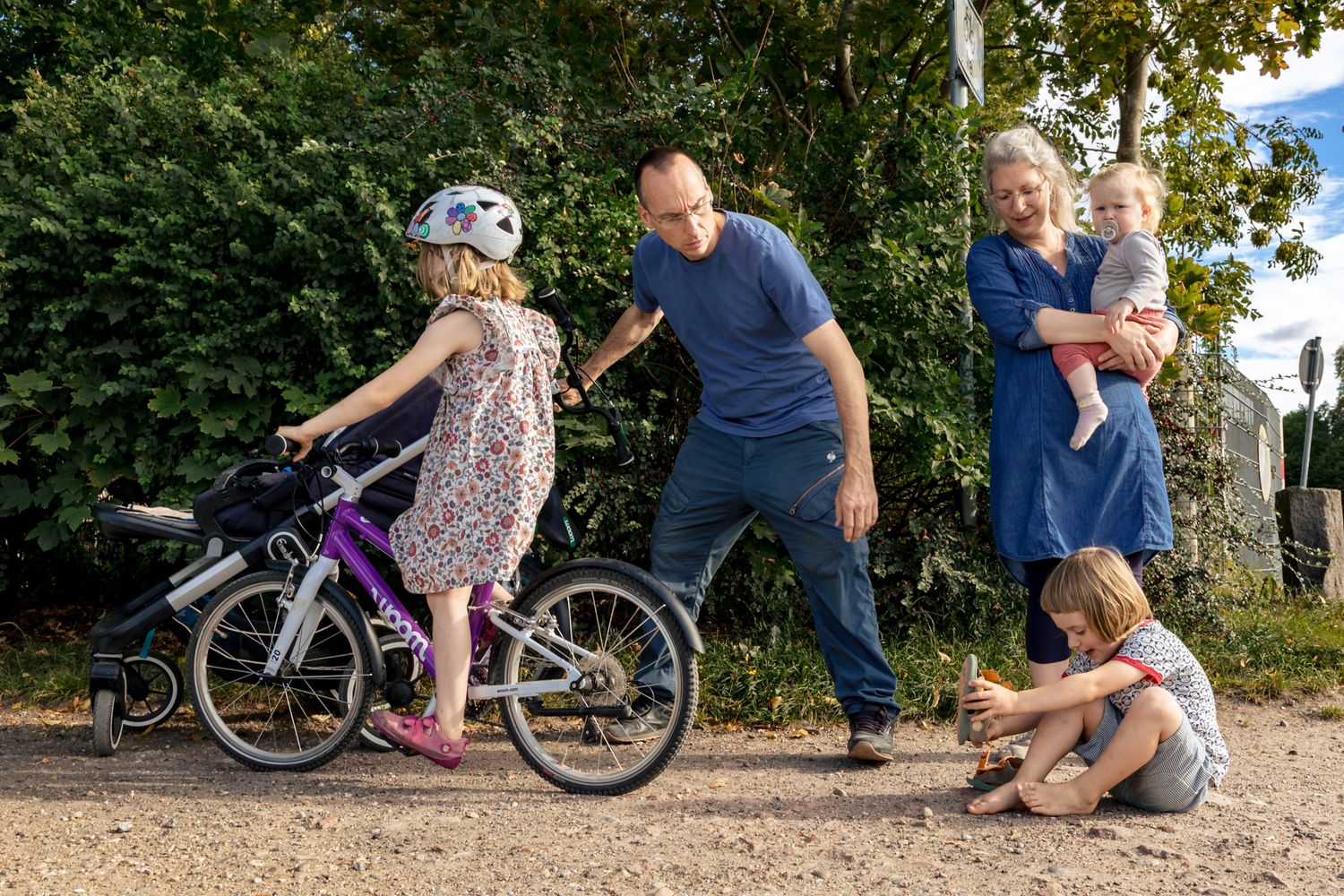 Familie beim Fahrradausflug – Vater hilft Kind auf dem Fahrrad, Mutter mit Baby im Arm – natürliche Familienfotografie Lübeck, Sylvia Fische