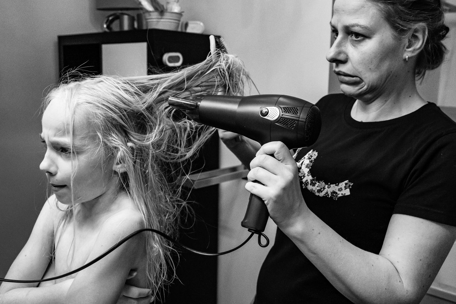 Mutter föhnt ihrer Tochter die Haare – Tochter ist launisch – dokumentarische Familienfotografie Lübeck, Sylvia Fischer Fotografie