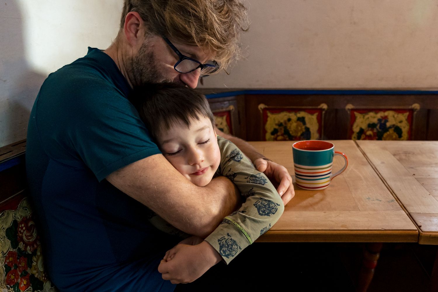 Papa hält Kleinkind zärtlich im Arm vor Kaffeetasse am Frühstückstisch - Ganztagesreportage bei der Familienfotografie Bad Oldesloe