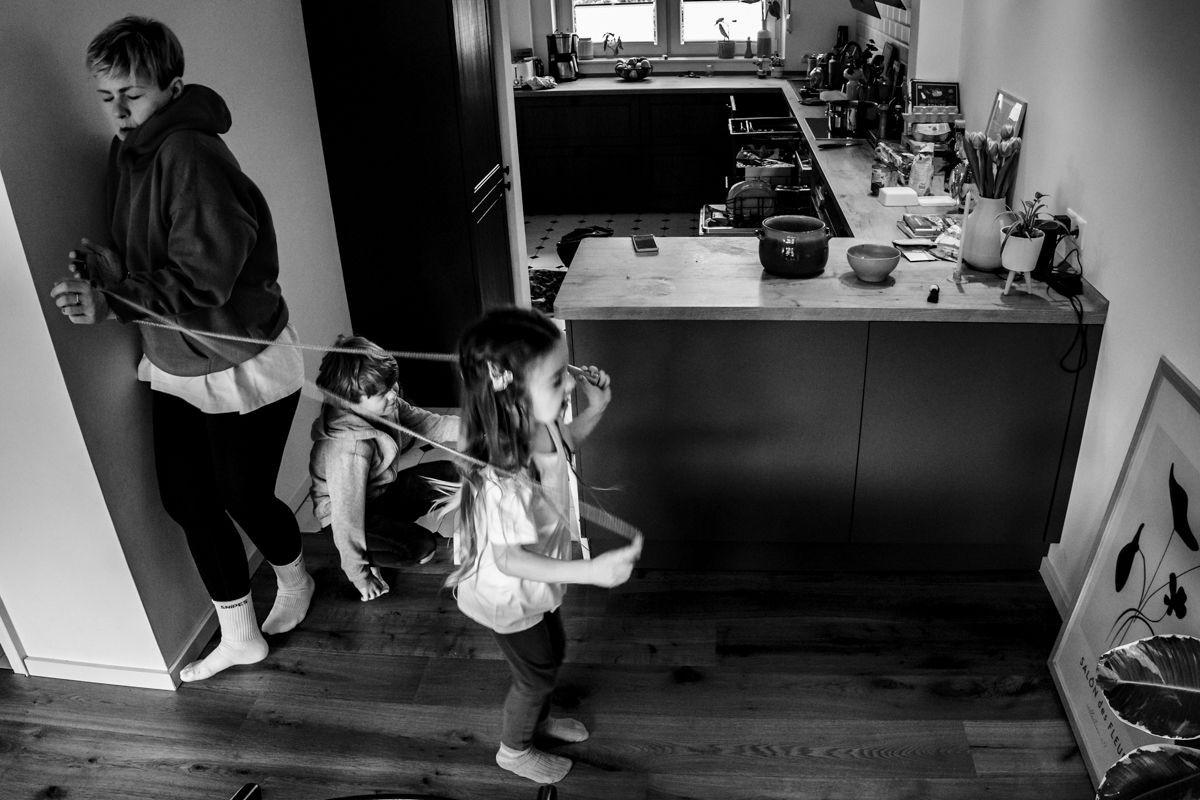Kind springt in der Küche Seil, Mutter versucht vorbei zu kommen - turbulenter Moment, Familienfotografie Lübeck