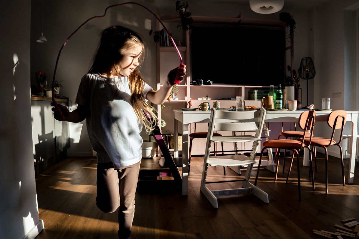 Kind springt im Wohnzimmer Springseil im Sonnenlicht - poetischer Moment, Familienshooting Lübeck
