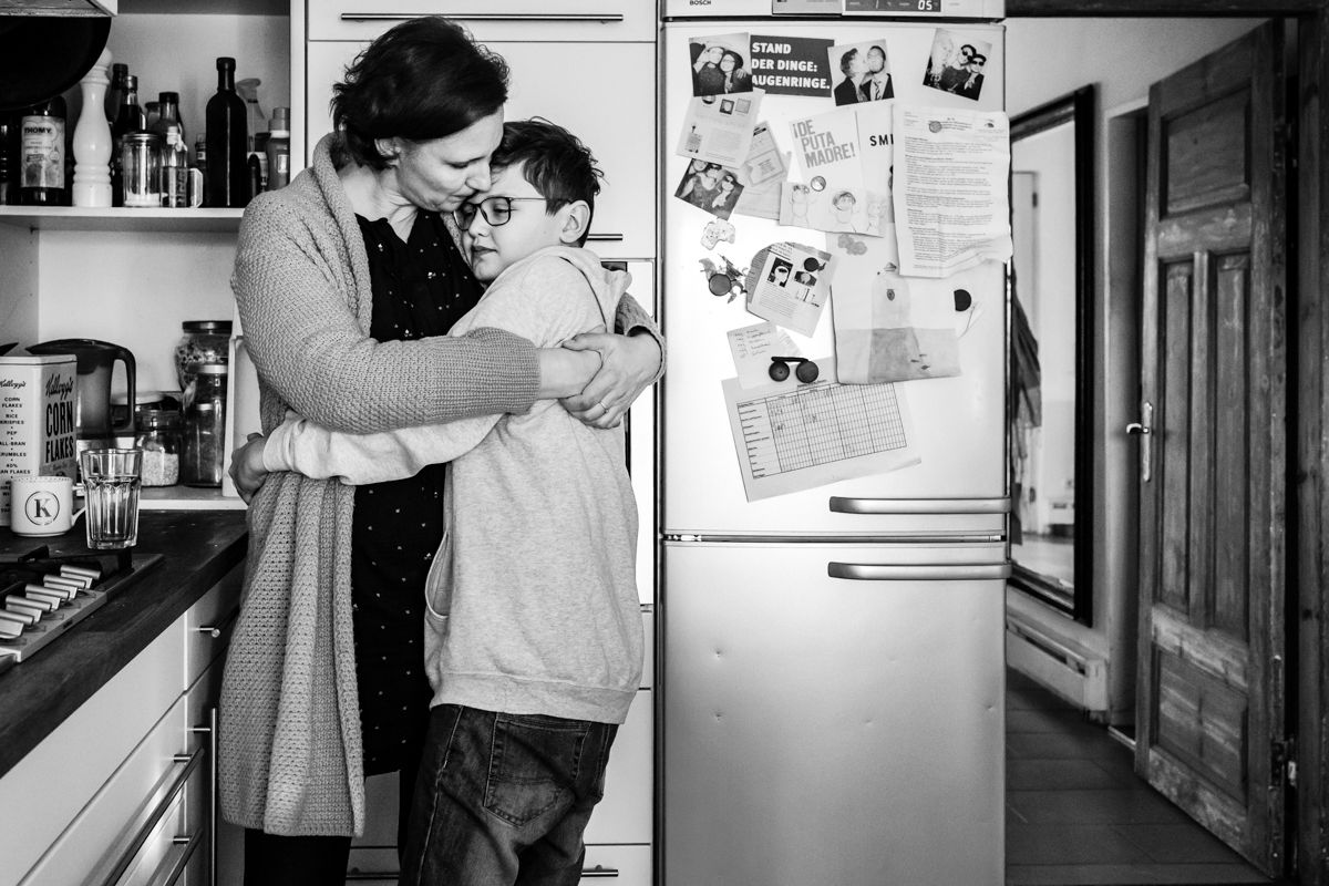 Mutter umarmt ihren Teenager in der Küche – stiller Moment der Nähe bei der Familienfotografie Lübeck
